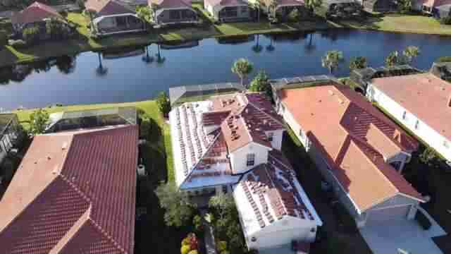 Tile roof under construction in residential neighborhood as seen from above. You can see a river and other homes in the background